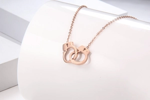 Detailed view of rose gold handcuff pendant necklace on a geometric white jewelry display