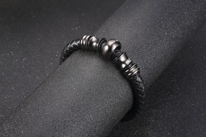 Macro view of woven black leather men's bracelet with dark chrome grooved metal beads
