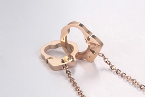 Detailed close-up of interlocking rose gold handcuff pendants with a sparkling zircon inlay