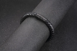Detailed view of black braided leather bracelet with matte metal push-button clasp for men