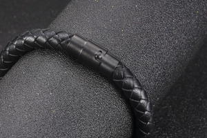 Close-up of black braided leather bracelet with matte cylindrical magnetic clasp