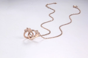 Detail of rose gold handcuff pendant necklace featuring small inlaid crystals and O-chain