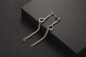 Gros plan de boucles d'oreilles cœur en acier titane avec longue chaîne à franges