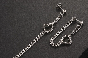 Détail macro des boucles d'oreilles cœur en acier titane argenté avec chaîne pendante