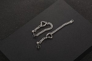 Détail de boucles d'oreilles cœur en acier titane argenté avec chaînes à pompons
