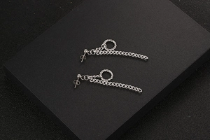 Macro-opname van zilveren titanium stalen kettingoorbellen met ring op zwarte textuur