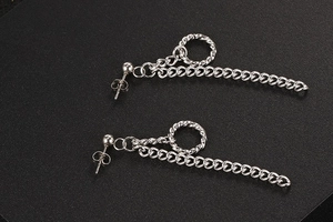 Macro-opname van zilveren titaniumstalen kettingoorbellen met metalen ringen op zwarte plaat