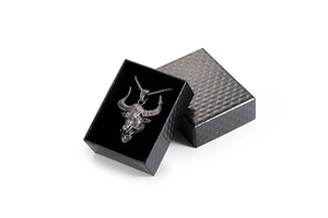 Close-up of vintage silver bull head pendant necklace inside a black textured jewelry gift box