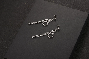 Macro-opname van zilveren titanium kettingoorbellen met holle hoepels en oorknopjes