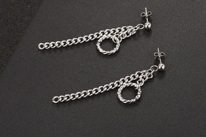 Detailopname van de zilveren titanium stalen kettingoorbellen op een donker mat oppervlak