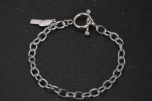 Makroaufnahme: Silbernes Titan-Kettenarmband mit OT-Knebelverschluss und rechteckigem Anhänger
