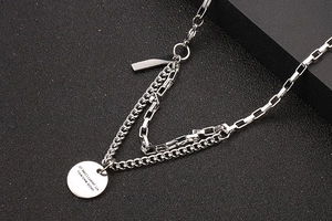 Macro view of double-layer stainless steel necklace with round pendant and engraved text