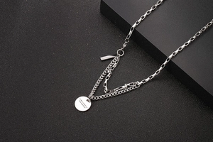 Detailed view of layered stainless steel chains with a round pendant on dark base