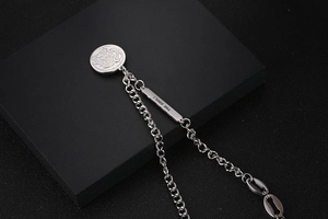 Macro view of silver OT buckle chain necklace with engraved soul tag and coin pendant
