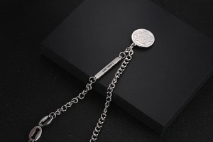 Macro detail of silver necklace with OT buckle, round coin pendant and soul tag