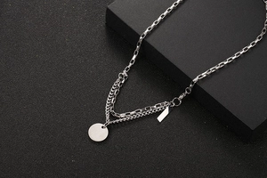 Detail view of double-layer silver stainless steel chain with round and bar pendants