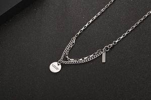 Detail of silver double-layer stainless steel necklace with engraved quote pendant