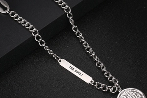 Macro view of silver link chain with rectangular Soul engraving and coin pendant detail