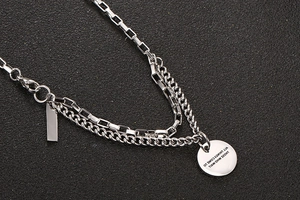 Macro view of double-layer stainless steel necklace with engraved round pendant detail