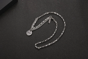 Detail of layered chain necklace with round pendant showing the engraved motivational slogan
