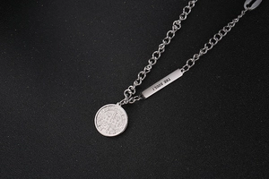 Macro shot of silver OT buckle necklace with rectangular The Soul tag and Saint Benedict medal