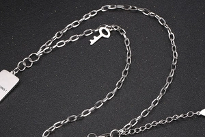 Detalle del collar de cadena plateada con colgante rectangular SOUL y amuleto de llave