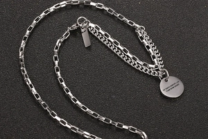 Detail of double-layer titanium steel necklace with engraved round tag and box chain