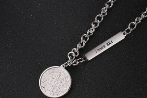 Close-up of silver OT buckle necklace with 'THE SOUL!' tag and religious coin pendant