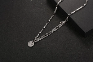 Macro view of double-layered stainless steel box chain necklace with engraved round pendant