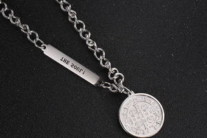 Macro view of stainless steel chain necklace with Saint Benedict medal and Soul tag