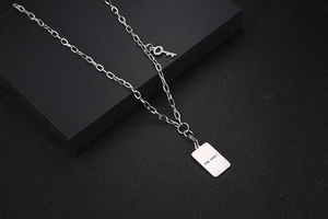 Detalle del colgante rectangular plateado pulido con grabado THE SOUL y un amuleto de llave