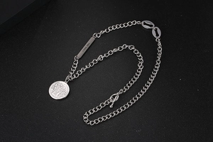 Close-up of industrial silver chain necklace featuring a coin pendant and engraved metal tag