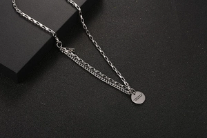 Macro detail of silver titanium steel layered chain and engraved circular pendant