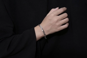 Close-up of a silver Figaro chain bracelet in titanium steel worn on a wrist