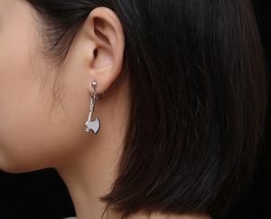 Close-up of a silver-toned 3D axe-shaped titanium steel earring on a model's ear