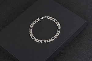 Close-up of polished silver Figaro chain with lobster clasp on black textured background