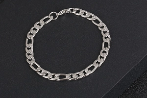 Detail of silver Figaro chain link bracelet with lobster clasp on black background
