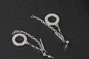 Detail van zilveren lange kwastoorbellen met Grieks patroon en strakke fijne kettingen