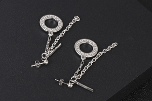 Detailweergave van zilveren kwastjesoorbellen met Griekse motieven en lange metalen kettingen