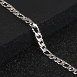 Polished silver Figaro link bracelet for men and women on a black luxury display stand