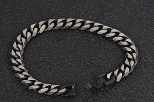 Détail macro du bracelet gourmette noir mat avec un fermoir métallique sécurisé