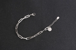 Dettaglio del bracciale a maglie silver con chiusura a moschettone e tag rotondo