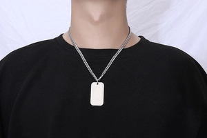 Close-up of brushed titanium dog tag pendant necklace worn on a black t-shirt