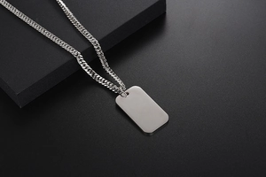 Close-up of a silver stainless steel dog tag pendant with thick curb chain on black blocks