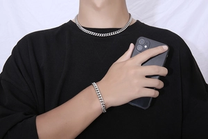 Ensemble collier et bracelet à mailles gourmette argentées pour homme sur t-shirt noir