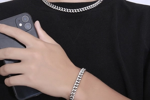 Gros plan d'un ensemble collier et bracelet gourmette en argent sur un T-shirt noir