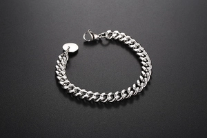 Détail du bracelet gourmette argenté avec fermoir mousqueton et pendentif rond métallique