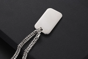Macro detail of silver rectangular military dog tag pendant with heavy curb chain link