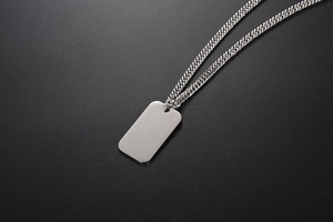 Close-up of blank silver rectangular pendant with classic cuban chain on dark surface