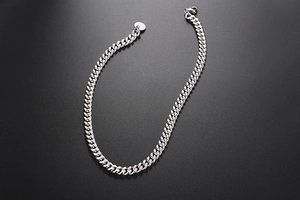 Vue macro d'un bracelet gourmette argenté avec fermoir homard et pendentif rond